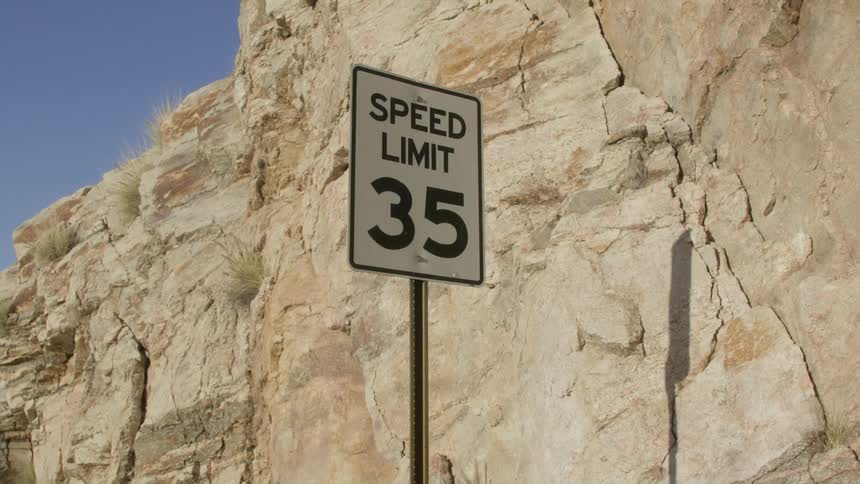 Speed limit traffic sign standing near the wall of a cliff in the desert at daytime