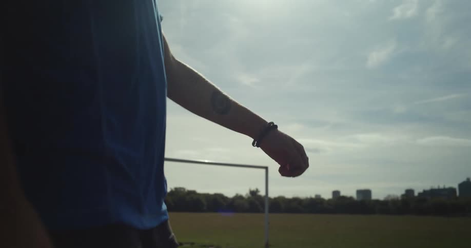 Female soccer player practices with soccer ball on sunny day with skyline in the background