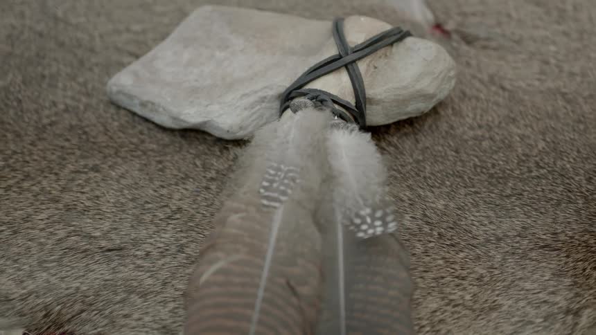 A tomahawk with feathers attached to it