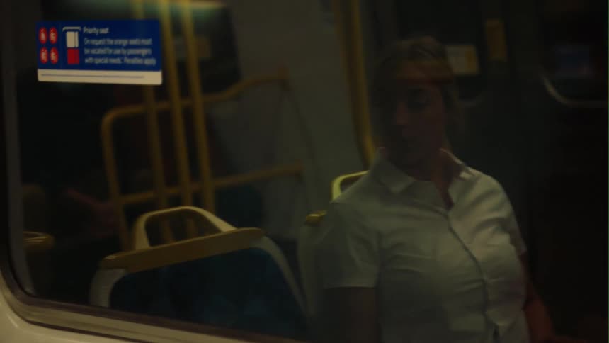 Woman with white shirt sits on passenger train traveling looking out the window