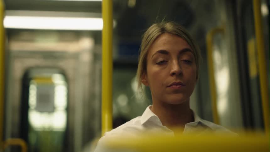 Blonde woman with ponytail and white shirt sits on train traveling