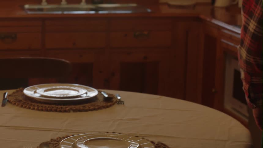 A man sets the table in his kitchen