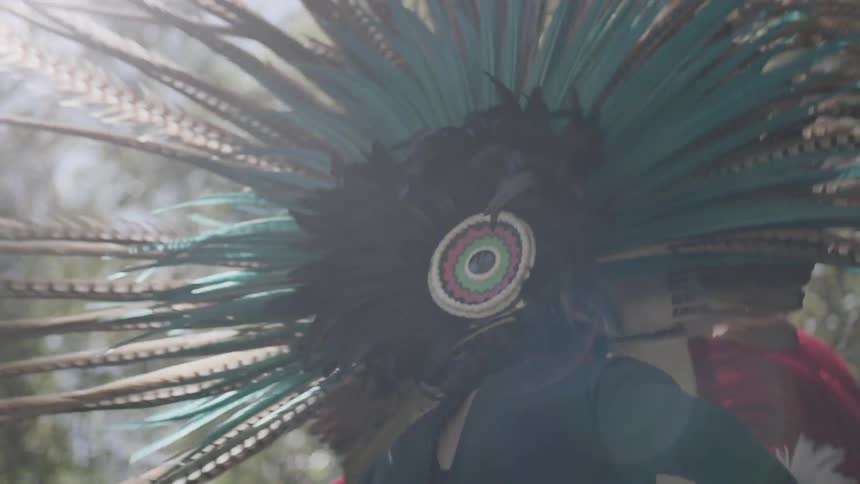 A native american wearing a large, feathered headdress while dancing