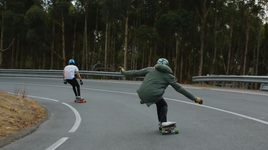 Slow motion of two people skateboarding is displayed