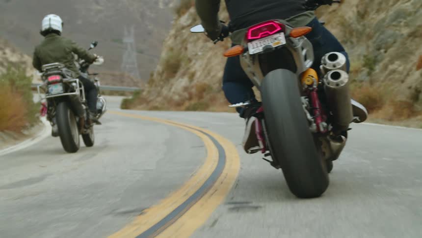 Two motorcycles are traveling on a winding mountain road