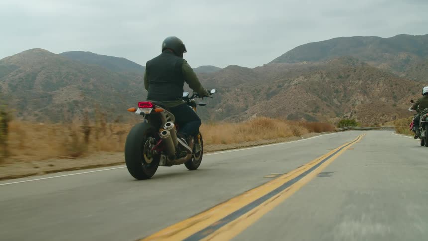 Two people are driving motorcycles in a rural area