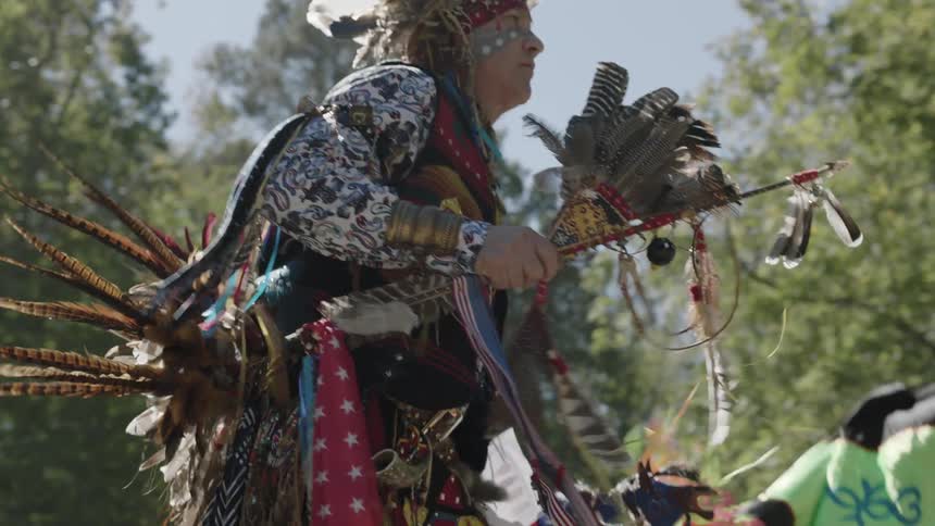 Several festively dressed native americans dance