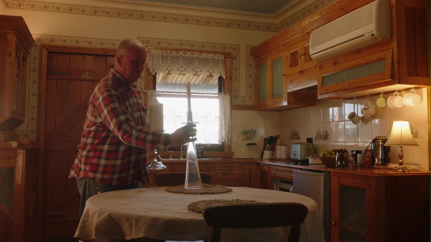 Man places candles in center of dining table set in the kitchen