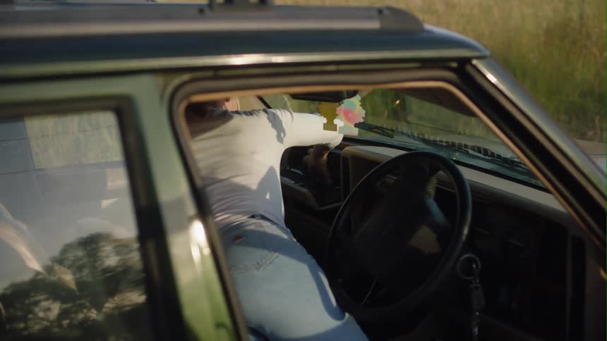 Woman in car parked next to field looks through glove compartment for a business card