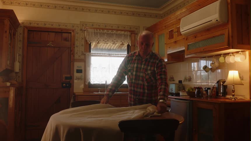 A man puts a table cloth on the kitchen table