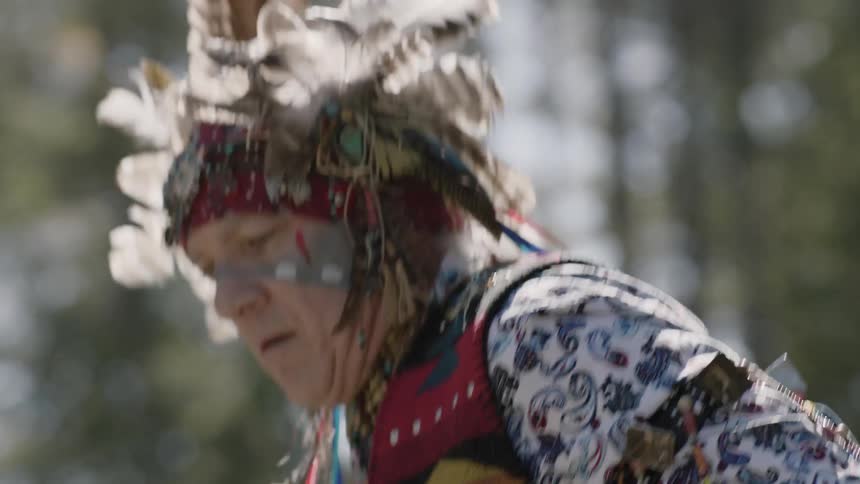 An older native american man performs a dance