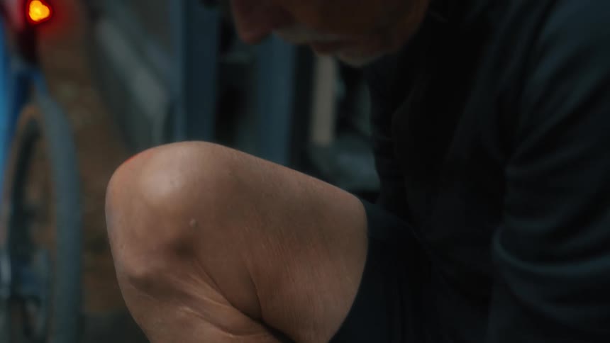 A man sits in his car door and ties his shoes