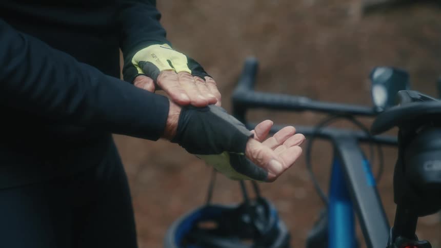 Cyclist stands near bicycle outdoor tightening their half gloves