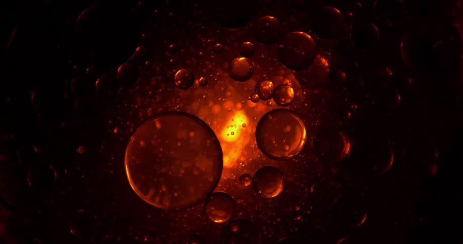 Bubbles floating and circling in liquid against black with a light glowing