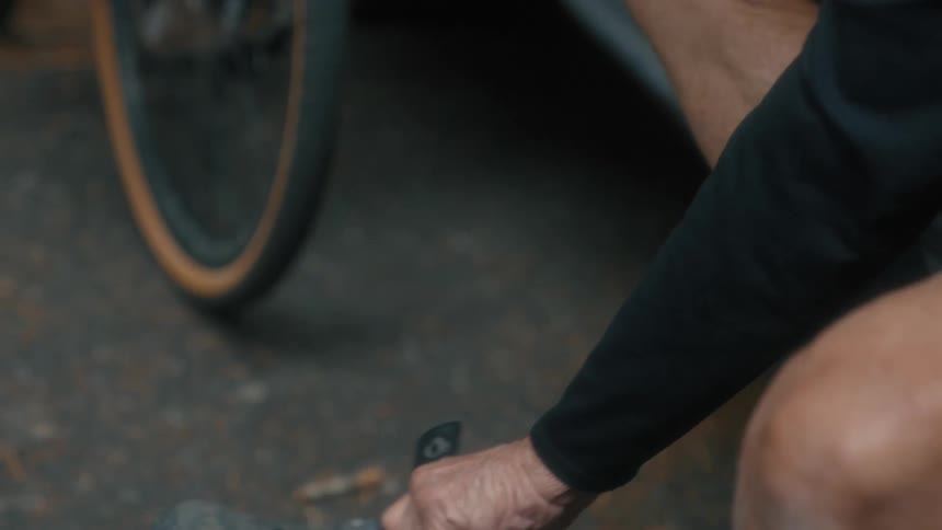 A man puts on cycling shoes while sitting halfway in his vehicle