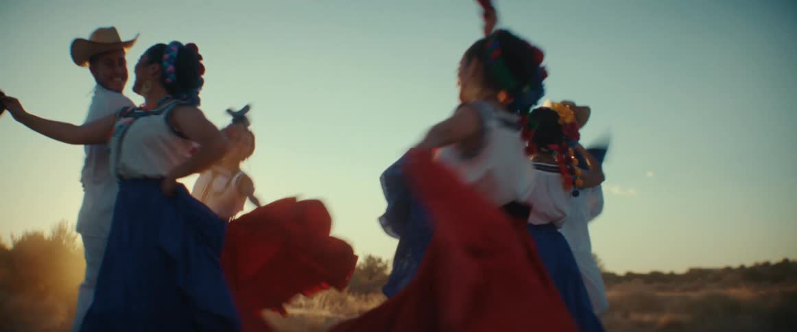 A group of men and women wave flags as they dance in a field