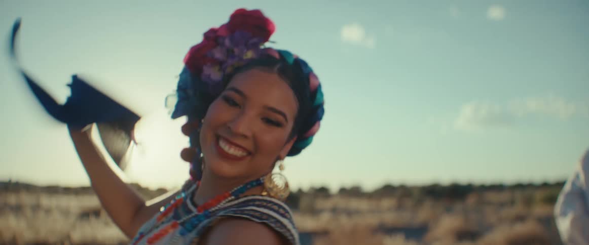 A woman waves a scarf while performing a traditional dance with a group of people