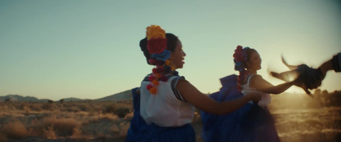A group of dancers wave scarfs while performing a traditional dance