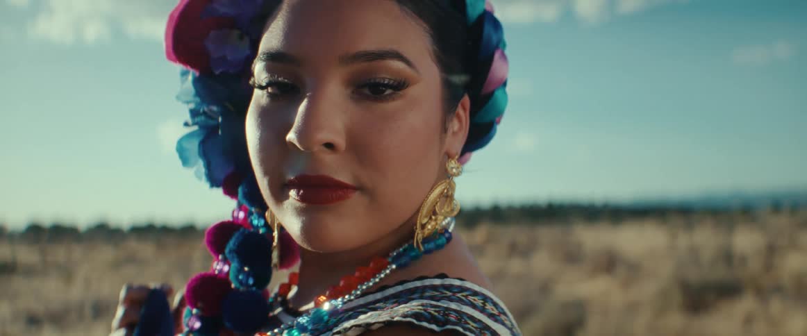 A woman with flowers in her hair stands in a field