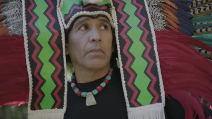 Man wearing elaborate headpiece performs a dance