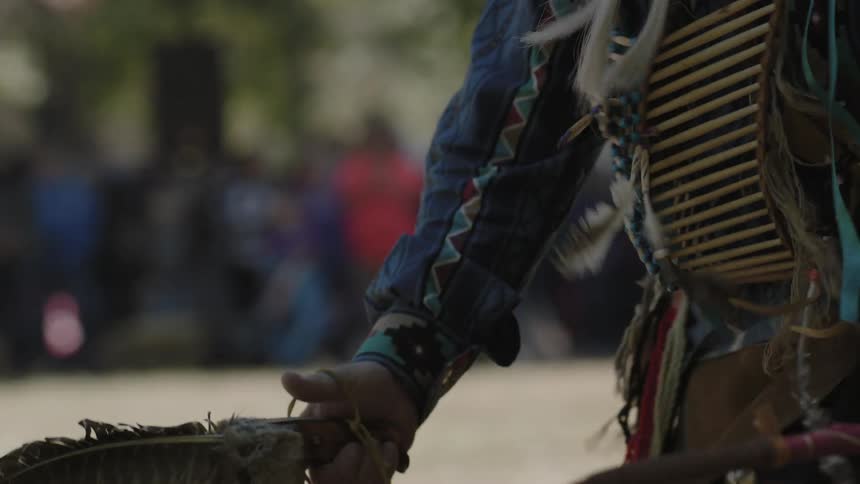 A native american in costume performs a dance