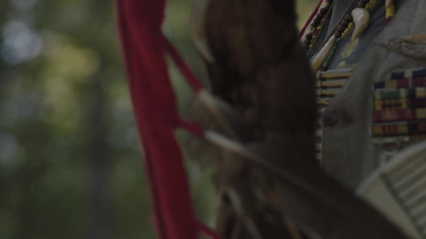 A native american man holding a bow and shield as he walks