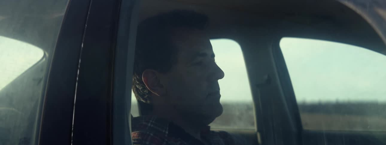 A sad looking man sits in a vehicle