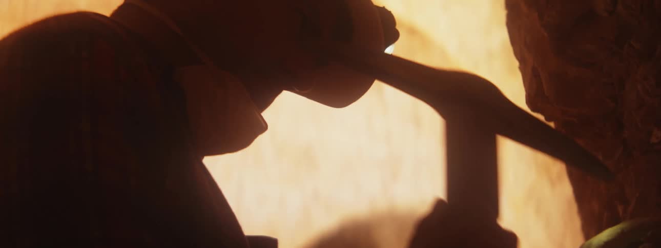 A miner working on rocks with a pick axe