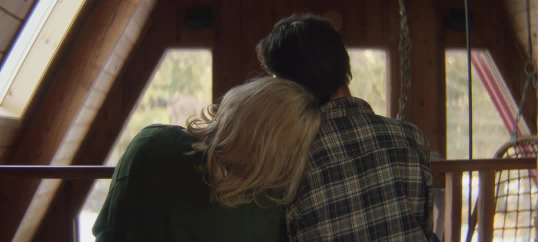 Couple sits cuddling while looking out window