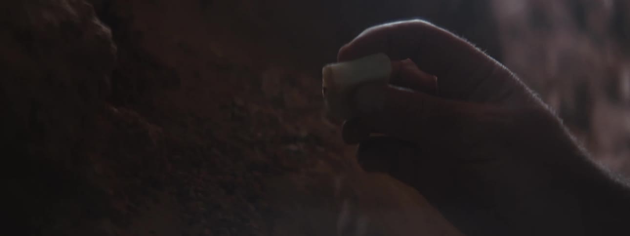 A man inspects a piece of quarts spinning and rotating it on his hands on a dimly lit area