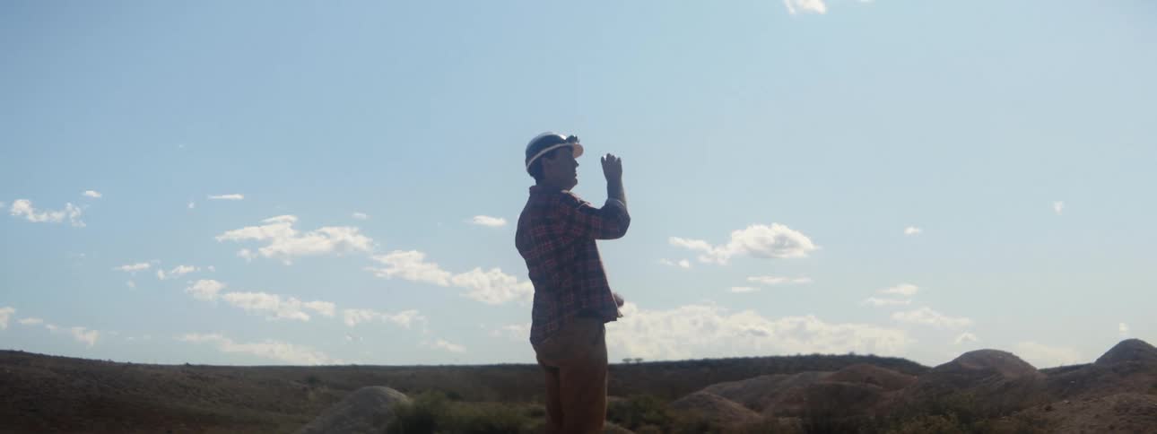 Man wearing headlamp stands outdoors examining object