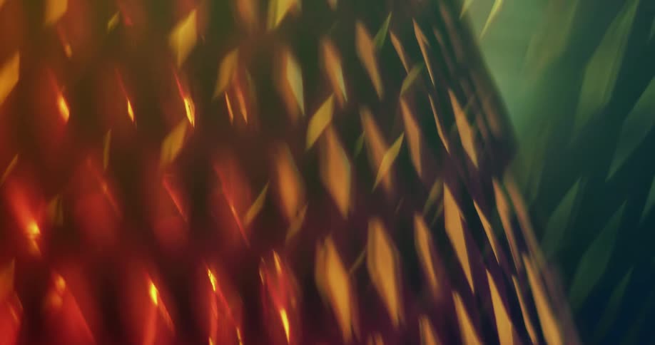 Close up of a rotating lamp shade weaved with diamond shapes projecting a diffuse yellow light
