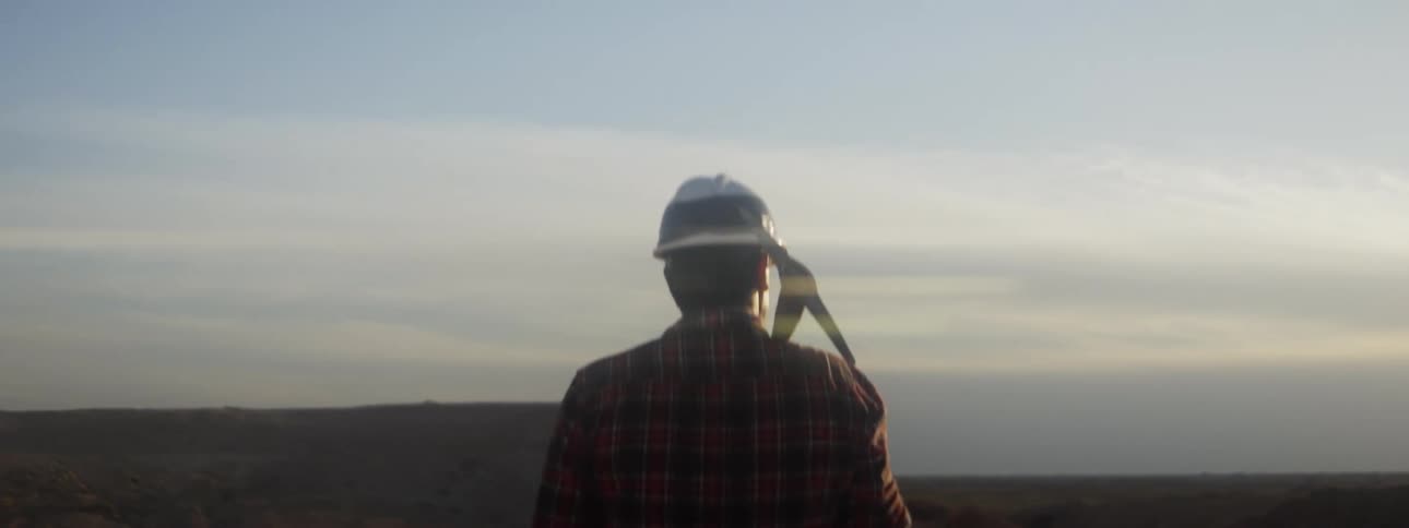 A man carrying a pick looks out at the landscape