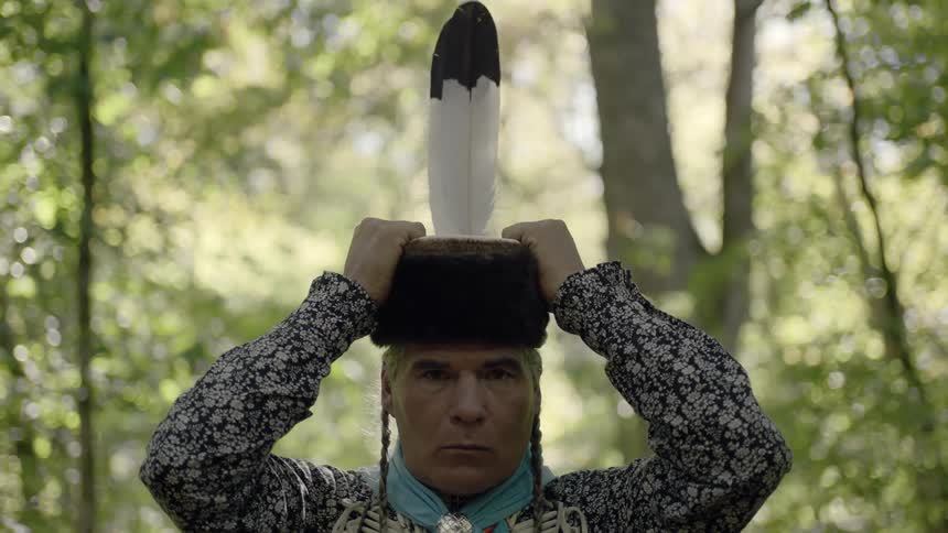 A native american man puts on a special headpiece