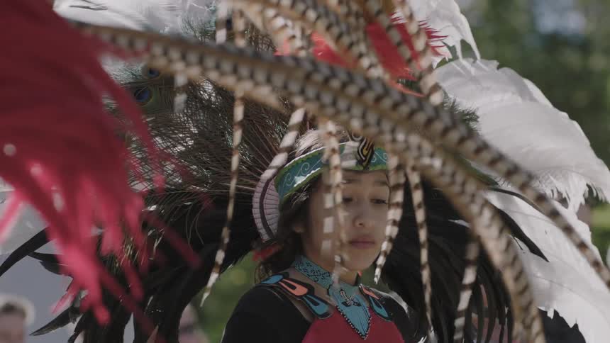 A young woman in a headdress looks down