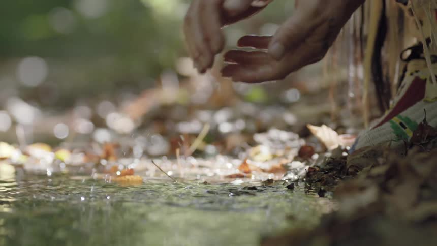 A person washes their hands in a stream