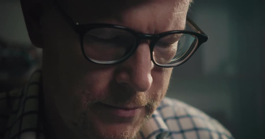Redhaired man wearing eyeglasses looks down while thinking