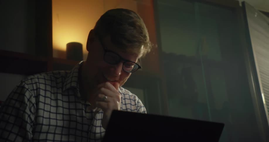 A man laughs and talks to someone on his computer
