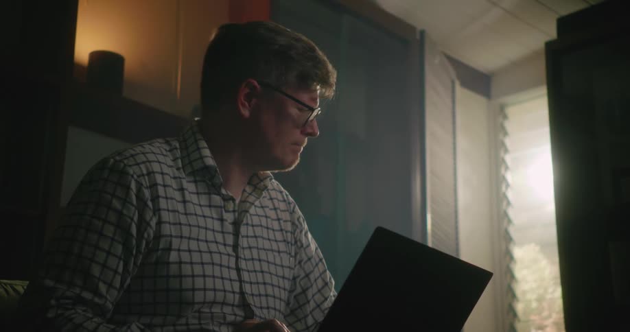 A man types as he looks toward the window