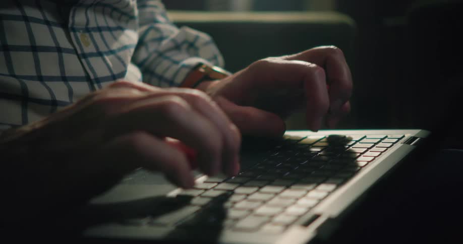 A mans hands are shown typing on a keyboard
