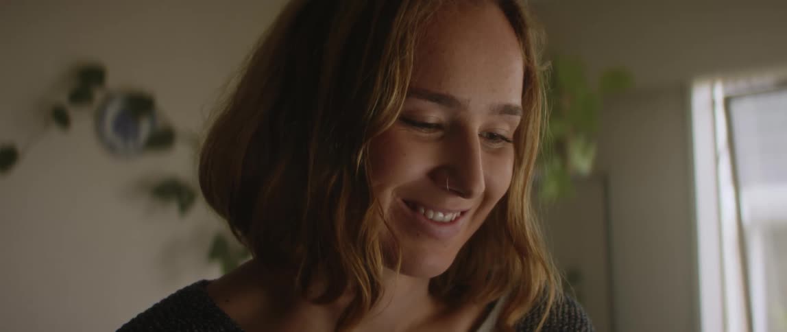 Woman at home near window smiles while watching