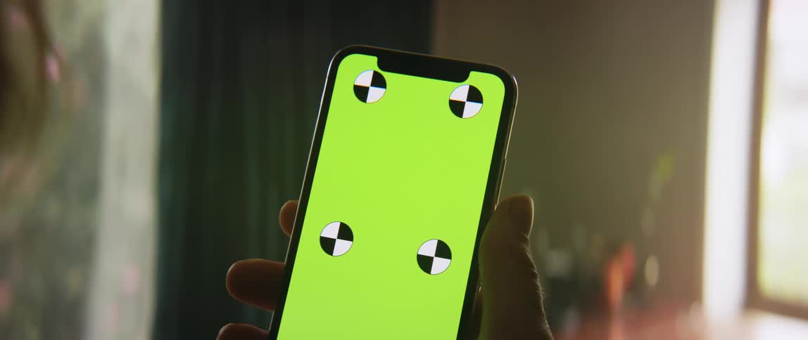 Someone is holding a cell phone in their hand that has a green screen