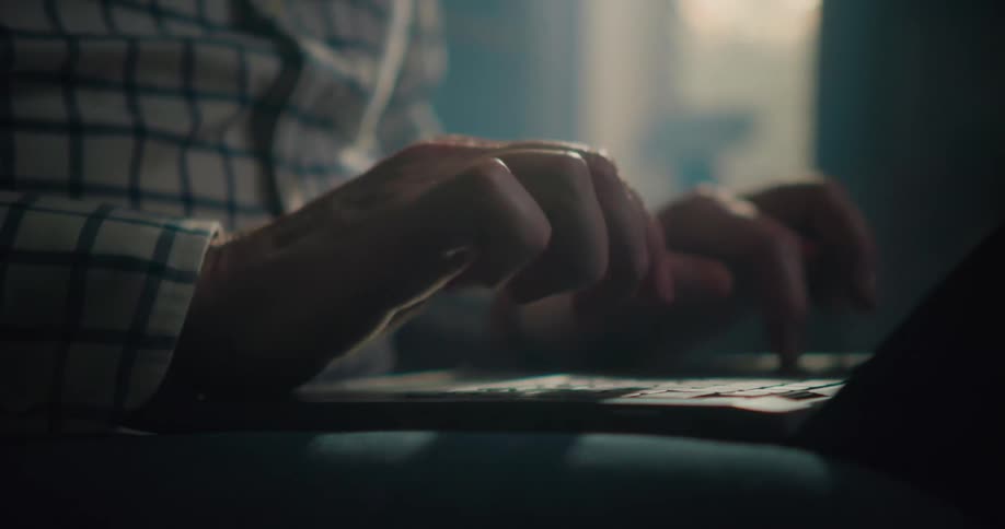 A man types on a laptop that is sitting on his knee