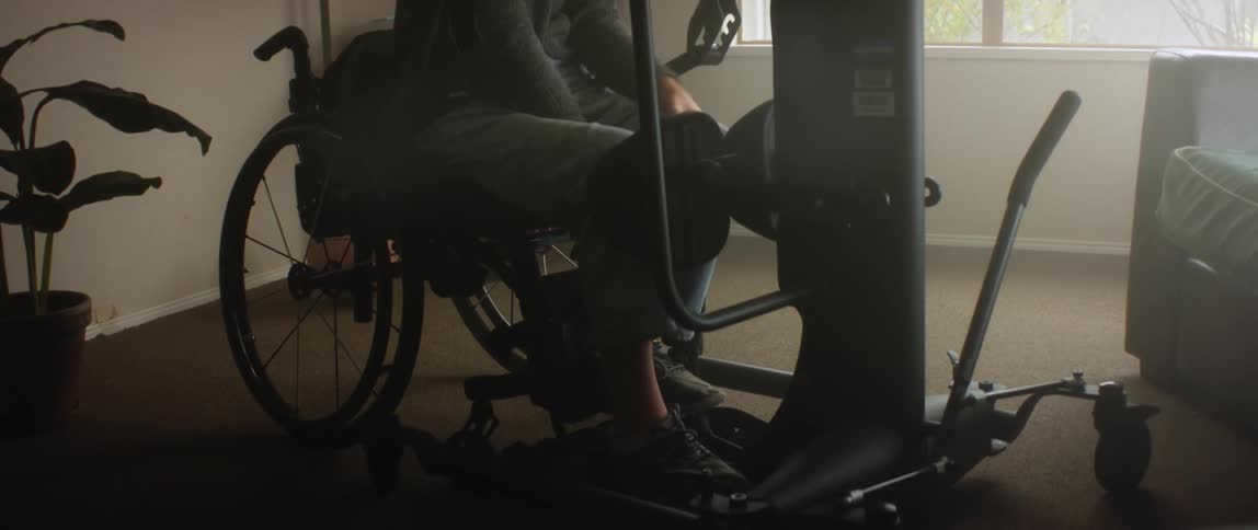 A woman in a wheelchair uses a machine to lift herself up at home