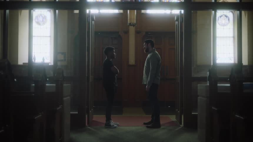 A man and a teenager speak at the back of a church