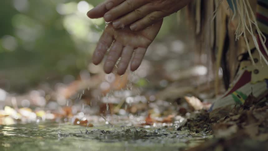 A person washes their hands in a brook
