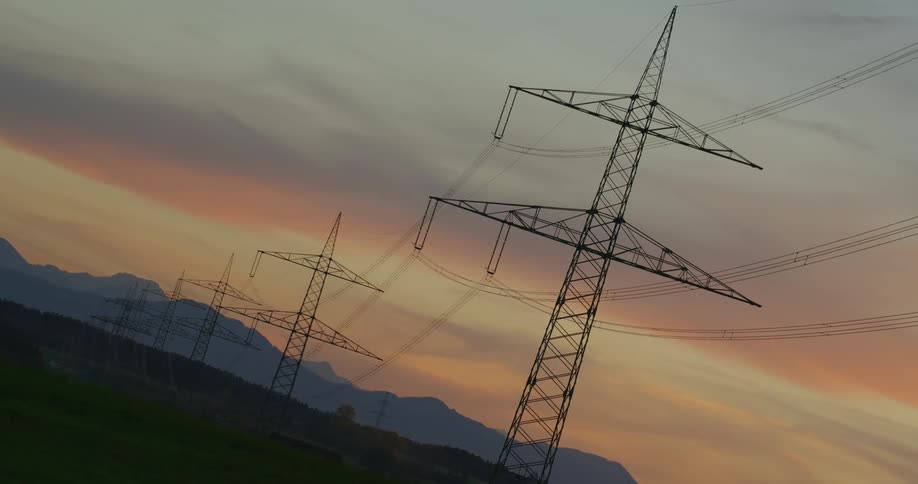 The sun sets over transmission towers in the countryside