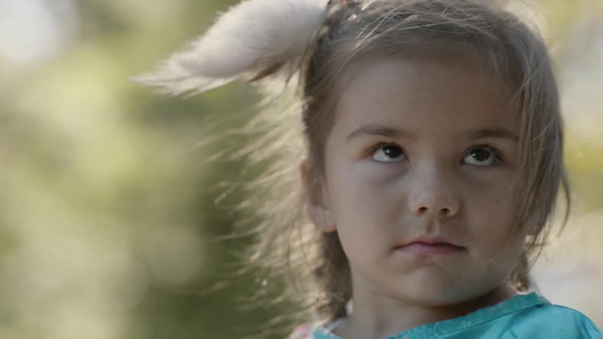 A breeze blowing through a little girl's hair and feathered hair decoration