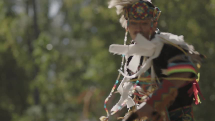 A native man dances around outside