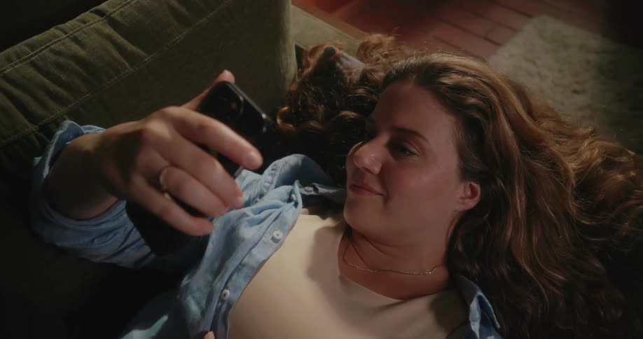 Woman reclining on couch takes a selfie